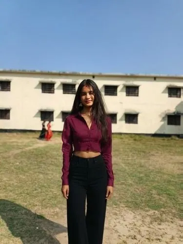 black shirt and crop ,an image of a young woman in pants and top,blurred background,a girl's smile,alumna,college student,midriff,concrete background