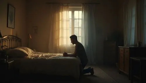 Interior of a dim bedroom, a man kneeling by the bed in silent prayer, morning light breaking through curtains. Cinematic soft lighting.,a man sits on a bed in a dark room with sunlight streaming thro