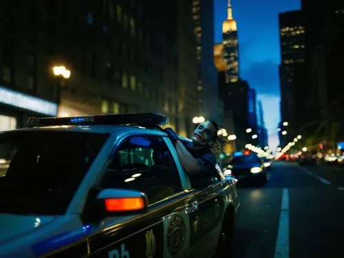 Police cars speeding through New York City at night,there is a cop standing next to a police car,new york taxi,nypd,cosmopolis,police car,nytr,gcpd,nyclu,police cruiser,gotham,patrol car,taxicab,polic