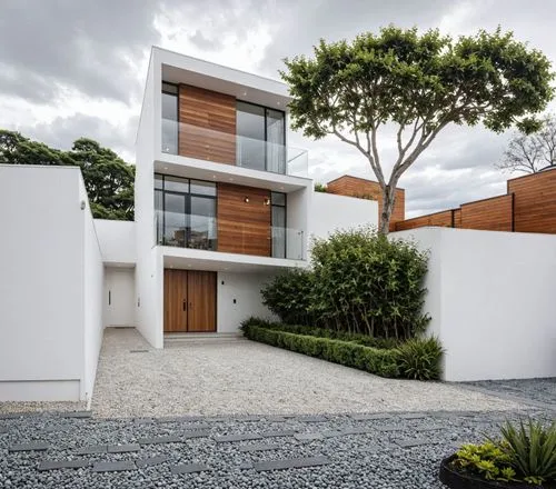 A photo-realistic rendering of a modern, minimalist two-story house with a contemporary design. the house is located in the middle of the image, with a large tree on the right side and a gravel drivew