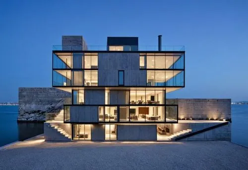 a house made out of blocks on the shore with windows,cubic house,cube house,modern architecture,dunes house,house by the water,cube stilt houses,danish house,modern house,glass facade,house with lake,