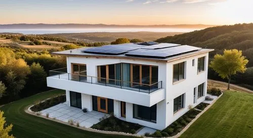 Aerial drone view from above, looking down at a contemporary three-story hempcrete residence. Focus on the organic, porous texture of the hempcrete walls underlined by natural wood window frames. The 