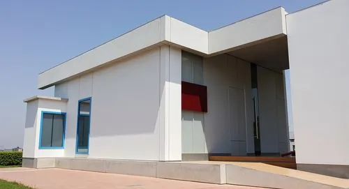 “Render exterior de un laboratorio ubicado en el garage de una casa. El diseño incluye paredes blancas, una pequeña cubierta roja sobre una puerta lateral con un acceso protegido, una ventana con marc