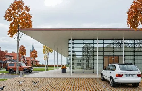 an outdoor structure that has birds around and one car in the middle,car showroom,carports,new town hall,cubic house,modern building,carport,residential house,folding roof,public library,modern house,