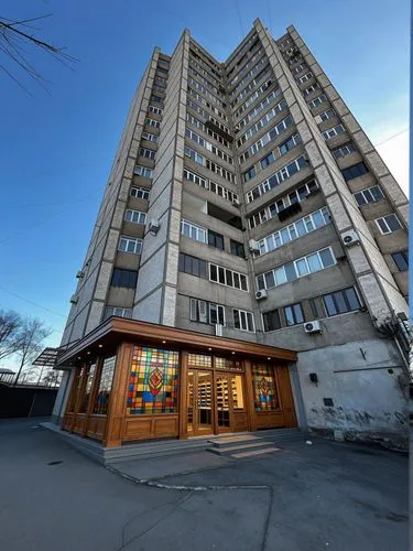 On the ground floor, instead of traditional blue iron outbuildings, there is a modern store characterized by stained glass windows and wooden elements.,a very tall building in the middle of town,headq