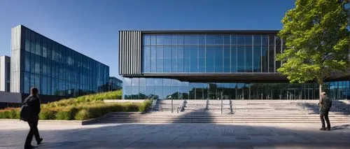 Modern institute building, public architecture, sleek glass facade, steel frame structure, minimalist design, angular lines, urban cityscape background, bright blue sky with few white clouds, warm sun
