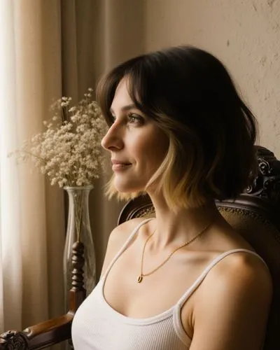 A realistic photograph presents a medium close-up portrait of a woman with a tousled chin-length dark brunette bob accented by bold blonde money-piece highlights framing her face, seated slightly righ
