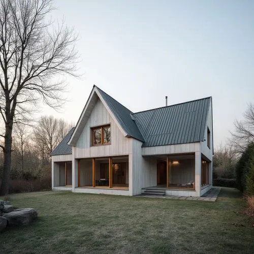  ,the white home sits on grass with some trees around it,timber house,wooden house,passivhaus,danish house,inverted cottage,clay house