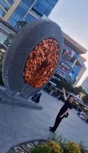 When the boy waves his hands, the orange statue spins like a sci-fi movie, radiating light and moving closer to the boy. Keep the facial details. Creative and realistic video - and a hand reaches out 
