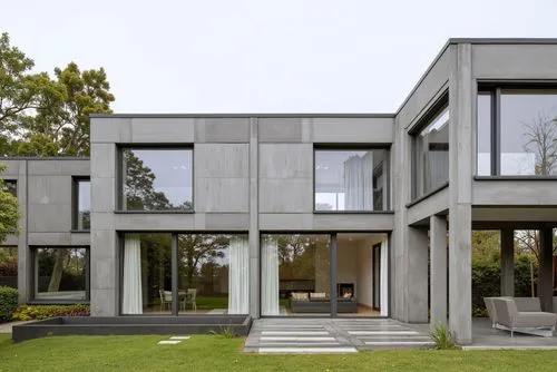 A modern concrete house with large geometric shapes, lush rooftop gardens, minimalistic glass windows, surrounded by dense greenery and urban sophistication,two grey buildings on grassy area in front 