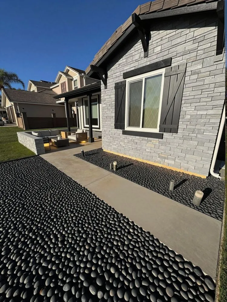 a backyard area that has lots of black pebbles covering it