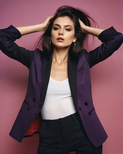 European appearance. A sassy model with straight, long, dark hair. She is wearing a black, loose blazer. The model stands straight in front of the camera, calm and relaxed. This is a studio shot. The 