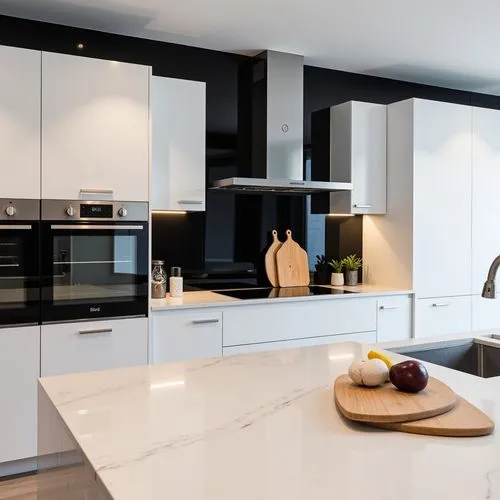 Modern kitchen with sleek white cabinetry and marble countertops. The space features a black accent wall with built-in appliances, including an oven and a stovetop with a hood. A minimalist sink and f