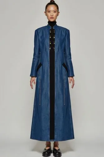 The denim  coat features a high mandarin collar and long sleeves.. A striking vertical black panel runs down the center front from collar to hem, adding bold contrast and elongating the figure. Decora