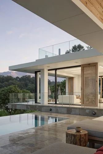 A photo-realistic shoot from the side about a modern, minimalist house with a pool and a stunning view of the mountains in the distance. the image also shows a serene outdoor living area with a tree s