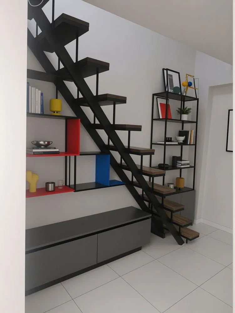 a book shelf under the stairs in a small room