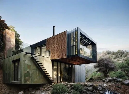 a large green house is near a steep cliff,cubic house,dunes house,cube house,inverted cottage,modern house,modern architecture,house in the mountains,cantilevered,house in mountains,mid century house,