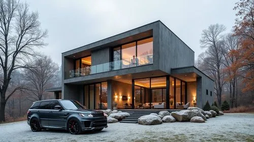 Autumn. Ultra-narrow vertical house with high glass from floor to ceiling, dark grey Range Rover Sport 2006 model in the foreground, many trees around, people are visible inside the house,a very nice 