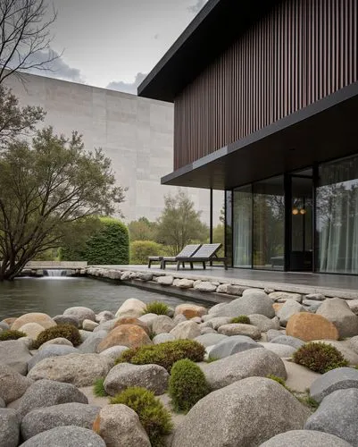 Dark wooden slats paired with reflective glass walls, overhanging minimalist roof, tranquil water features blending with misty surroundings, natural stone integration, serene and sophisticated design.