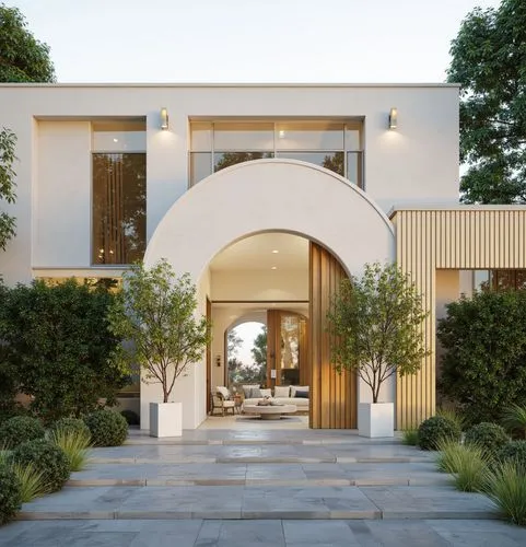 A modern Mediterranean-inspired facade with clean lines and soft tones. The entrance features a grand arch, flanked by vertical wooden panels and lush greenery. The glass windows reflect the soft glow