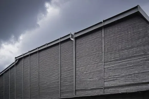 Industrial building, modern architecture, metal roofing system, corrugated galvanized steel sheets, silver-gray color, rivets, bolts, sleek lines, angular structure, sloping roof, skylights, rectangul