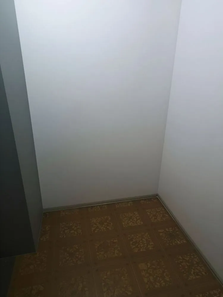a bathroom stall with flooring and white walls
