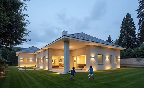 two people are walking towards a modern house at dusk,villa,modern house,residential house,cube house,holiday villa,house shape,artificial grass,cubic house,family home,forest house,golf lawn,turf roo