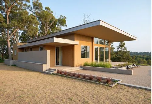 A modern house with a flat roof, rammed earth walls, large glass panels, and timber columns, set in an open grassy field with eucalyptus trees, warm earthy tones, and minimalist landscaping.,a modern