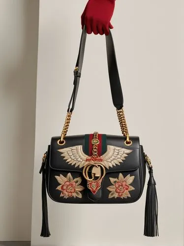 Inspired by Renaissance symbolism with a modern aesthetic, this Gucci women's bag is crafted from supple cowhide leather and embroidered with totems of angels and Satan.,someone is holding a black han