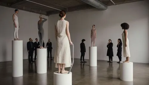 A cinematic documentary photograph of a contemporary art installation inside a dimly lit industrial gallery with exposed concrete ceilings, visible ductwork, and polished brownish-grey concrete floors