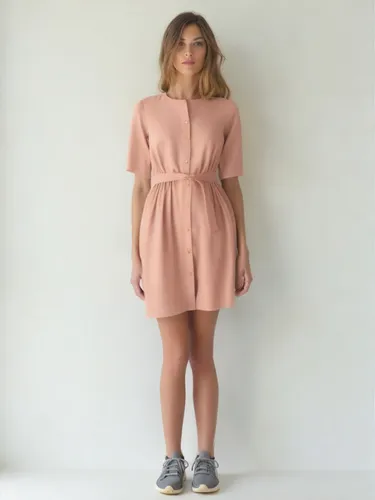 a woman wearing a pink dress is standing against a wall,hemline,shirtdress,neopolitan,hemlines,peach color,khaki,minidress,neapolitan,peach tan,women's clothing,shirtdresses,neutral color,taupe,vestid