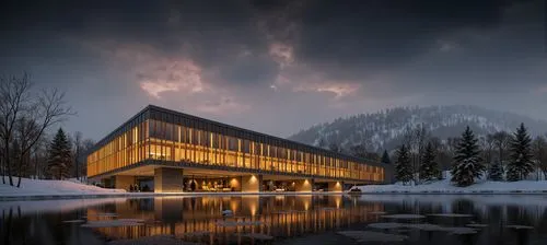 A photo-realistic shoot from a bird's eye view about a modern building with a wooden facade, situated on a frozen lake surrounded by snow-covered trees in a misty forest. the image also shows a serene