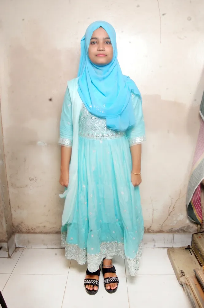 woman in hijab standing on tile floor next to wall
