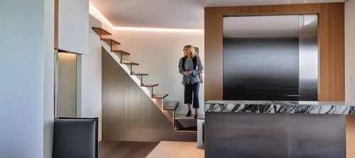 a woman standing in the foyer near some stairs,walk-in closet,penthouses,interior modern design,hallway space,modern room,contemporary decor,modern decor,wardrobes,metallic door,modern minimalist bath