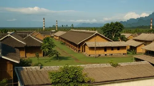 "A row of wooden buildings, likely company-owned housing for workers of the Batavia Oil Company in Balikpapan, 1930s. The buildings are simple and functional, with thatched roofs and wooden walls. A s