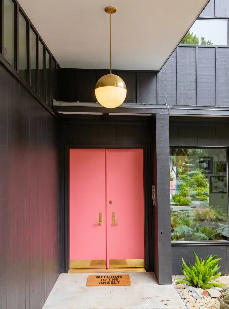 the entrance to the pink door has a white mat on the ground