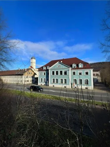 Street front of a large traditional cotton mill in southern Germany.,the blue building has a very tall tower,bad urach,brauerei,clausthal,wildbad,residenz,waldshut,krumbach,the bavarian railway museum