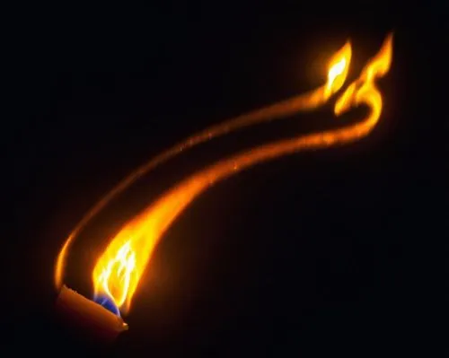 The flame of a candle lights up the darkness.,a lit candle with a dark background with the flames coming out of it,flaming torch,fire ring,dancing flames,torch tip,burning torch,torch,light drawing,fl