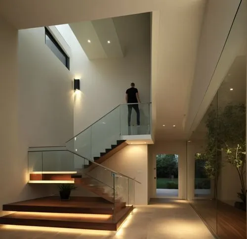 Renderiza un espacio interior moderno de doble altura, con diseño arquitectónico contemporáneo. El ambiente debe incluir una escalera flotante con barandales minimalistas de cristal o acero inoxidable
