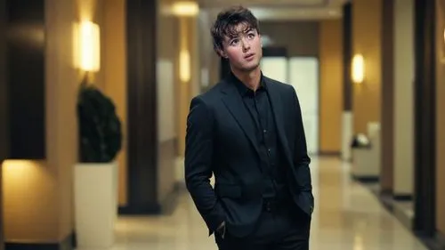 КЛИЕНТ ВСЕГДА ПРАВ - THE CLIENT IS ALWAYS RIGHT,a man is standing in the hallway of an apartment,blur office background,hotel man,spy visual,black coat,dark suit,black suit,suit,spy,professedly,bellbo