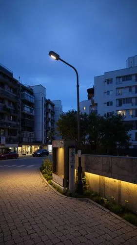 A quiet urban street corner in Taipei at dusk. A weathered public utility box stands at the base of a street lamp, its surface left unchanged with visible stickers and wear, blending into the redesign