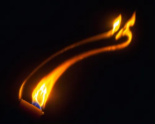 The flame of a candle lights up the darkness.,the bright orange fire is in the air,flaming torch,fire ring,dancing flames,burning torch,torch,light drawing,torch tip,flame spirit,fire background,pyrom