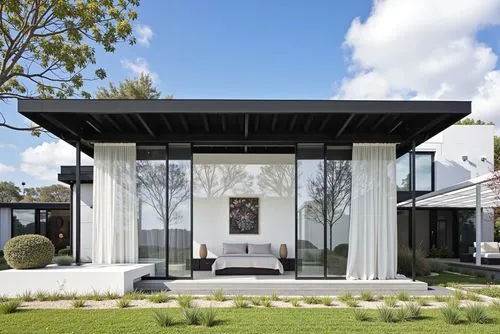 A modern, minimalist house with a minimalist design, featuring a large glass walled entrance and a black metal roof. the house is situated on a grassy area, with a clear blue sky and fluffy white clou