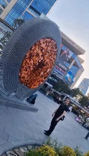When the boy waves his hands, the orange statue moves like a sci-fi movie, moving and spinning in a circle, emitting light and approaching the boy. Preserve facial details. Creative and realistic vide