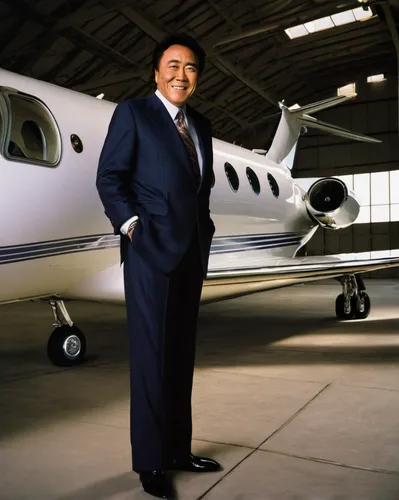 Robert Kiyosaki standing by a private jet in an airplane hanger.,business jet,corporate jet,mukesh ambani,ceo,private plane,black businessman,learjet 35,billionaire,an investor,executive toy,business 