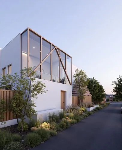 A minimalist modern house with a white facade and large glass windows framed by wooden beams. The house is surrounded by natural landscaping, with a narrow road in the foreground and a twilight sky in