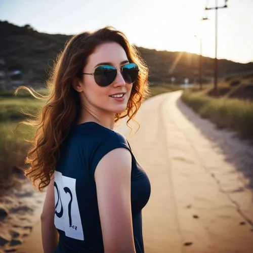 the girl in glasses poses on the road,beach background,girl on the dune,girl in t-shirt,sun glasses,sunglasses,female runner,beach walk,aviators,wayfarers,woman walking,walk on the beach,golden hour,f