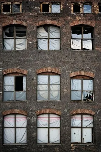 Front photo about Many broken windows on old abandoned warehouse.,four large windows covered with a sheet are displayed,row of windows,old windows,broken windows,warehouses,brickyards,tenements,window