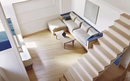 a living room is seen from above, with a sofa and coffee table,wooden stair railing,hallway space,wooden stairs,prefab,outside staircase,smart home