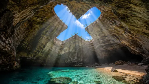 blue skies, grotto, a hole shaped like an X, sunlight passing through the hole
,the blue water in a mountain stream is a light source for the cross,sea caves,cave on the water,blue cave,blue caves,nar